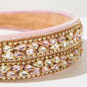 Gros plan d'un serre-tête en velours rose avec strass et cristaux sertis à la main