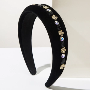 Detailed close-up of a black velvet headband with gold flowers and sparkling rhinestones