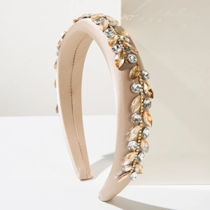 Close-up of champagne satin sponge headband with amber crystal leaf embellishments