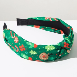Detail van groene kersthoofdband met rendieren, bomen en zuurstokken prints erop