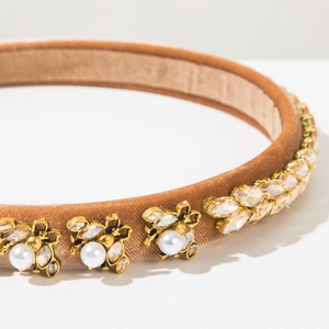 Detailed close-up of velvet headband with golden bees, pearls and champagne rhinestones