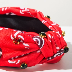 Vue macro du serre-tête noué en satin rouge avec motifs blancs et strass colorés