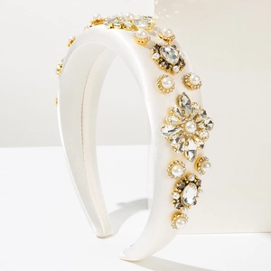 Détail d'un serre-tête en satin blanc orné de perles, cristaux et fleurs dorées