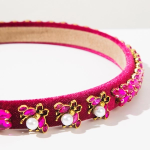 Detailed macro view of golden bee ornaments on magenta velvet headband with crystals
