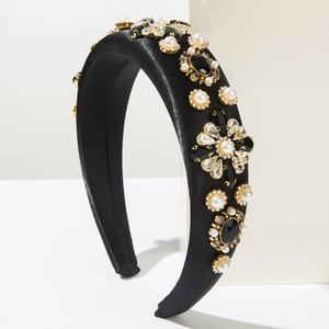 Détail d'un serre-tête en satin noir orné de fleurs en perles et strass brillants et élégants