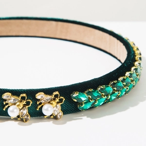 Detailed macro view of dark green velvet headband with gold bees and green crystals
