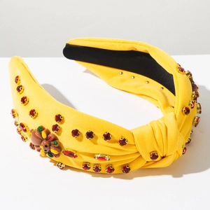 Macro detail of yellow knotted headband with red rhinestones and turkey motif