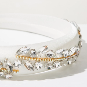 Macro detail of white satin headband with leaf-pattern crystals and golden rhinestone settings