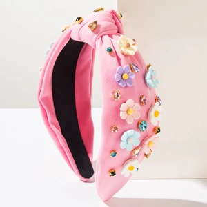 Détail d'un serre-tête baroque en tricot rose avec fleurs 3D colorées et strass brillants