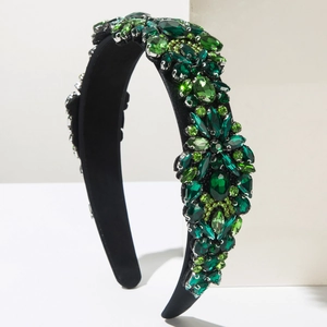 Detailed view of green rhinestones and emerald crystals on a luxury black headband