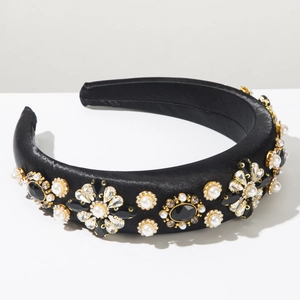 Détail d'un serre-tête en satin noir avec perles et strass sur fond blanc épuré