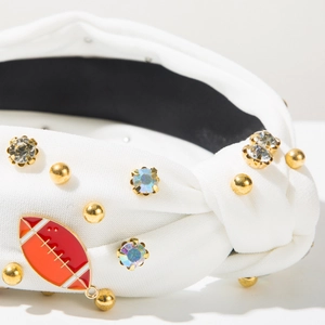 Dettaglio della fascia sportiva bianca con strass colorati e ciondolo da football