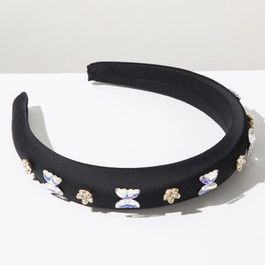 Détail d'un serre-tête en éponge avec papillons en strass et fleurs dorées décoratives