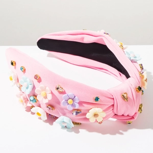 Détail du serre-tête en tissu rose avec des fleurs 3D colorées et des strass étincelants