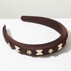 Détail du serre-tête en velours marron avec strass dorés en forme de papillon et fleur