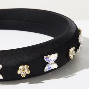 Détail macro du serre-tête en satin noir avec ornements papillon et fleur en cristal