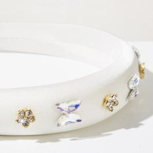 Vue détaillée du serre-tête en satin blanc avec fleurs dorées en strass et papillons cristal