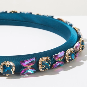 Detail of teal satin headband with butterfly jewels and blue gemstones in gold settings