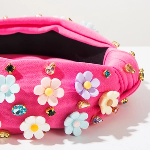 Détail d'un serre-tête noué rose fuchsia avec fleurs 3D en résine et strass colorés