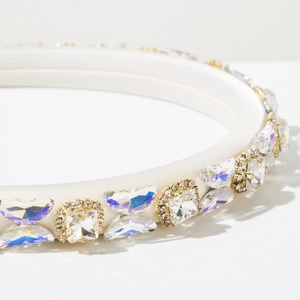 Detail of white sponge headband with gold-set crystals and rhinestones in macro view