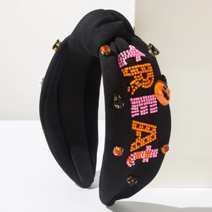 Detail of beaded TREAT text and pumpkin charms on a knotted Halloween headband