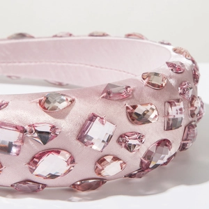 Macro shot of pink satin headband featuring various hand-sewn crystal rhinestones