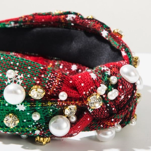 Close-up of a wide knot headband with red and green plaid fabric, pearls and rhinestones