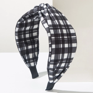 Dettaglio del cerchietto in tessuto a scacchi bianco e nero con elegante nodo intrecciato