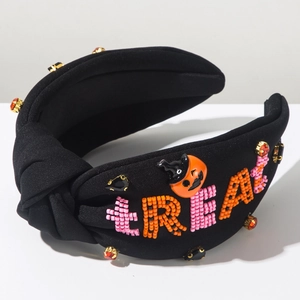 Detail of Halloween knot headband with beaded TREAT text and pumpkin wizard hat accessory
