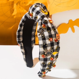 Détail d'un serre-tête Halloween avec carreaux noir et blanc, crânes et pierres oranges