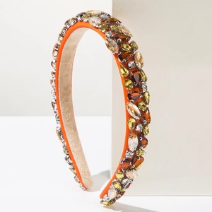 Détail d'un serre-tête baroque de luxe en tissu orange avec des strass ambrés étincelants