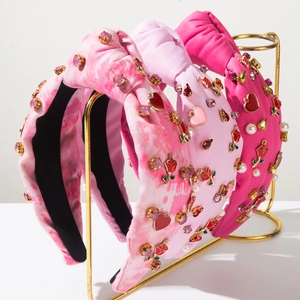 Detailed view of three knotted headbands with rhinestones and pearls on a gold rack