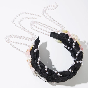 Close-up of woven black headband with pink flowers and hanging pearl tassel details
