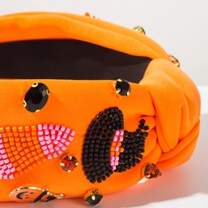 Macro view of orange Halloween headband featuring intricate hand-beaded pumpkin details
