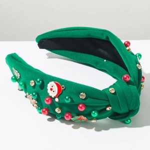 Dettaglio macro di un cerchietto natalizio in maglia verde con Babbo Natale e perle