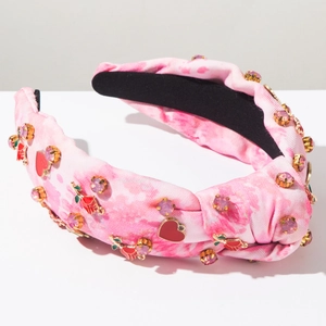 Close-up of pink tie-dye knotted headband with rhinestones, enamel hearts and cherry charms
