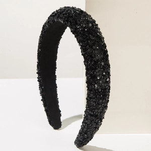 Close-up of wide-brimmed black headband featuring dense shimmering sequins and velvet lining