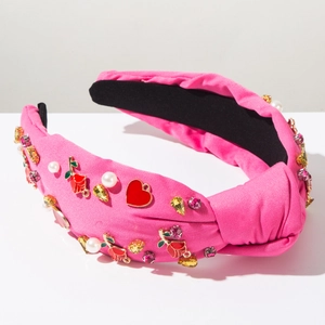 Close-up of pink knotted headband featuring heart charms, pearls and floral crystal details