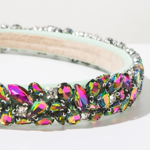 Détail d'un serre-tête baroque en tissu vert clair avec des strass étincelants colorés