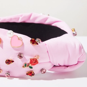 Detail of pink knotted headband with heart pendants, red roses, and inlaid pearls
