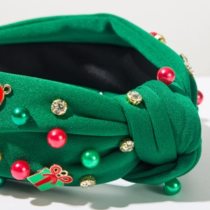 Dettaglio del cerchietto natalizio verde con decorazioni di perle e ciondolo regalo