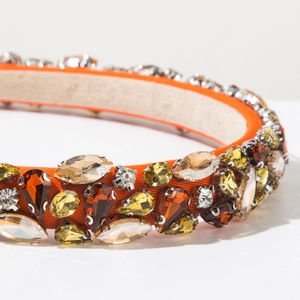 Gros plan sur serre-tête orange en velours avec strass ambrés et gemmes de luxe