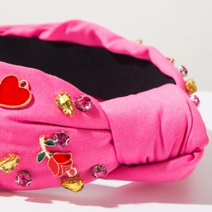 Close-up of rose pink knotted headband featuring heart charms and floral rhinestone details