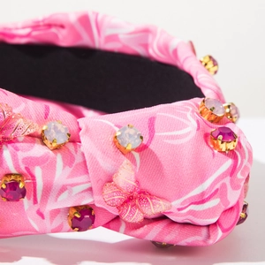 Detail eines rosa Batik-Haarreifens mit Strasssteinen und goldenen Schmetterlings-Applikationen