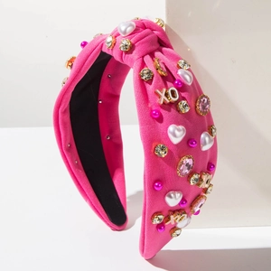 Detail van roze geknoopte hoofdband met XO metalen bedels, parels en kristallen