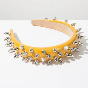 Close-up of yellow patent leather headband with silver punk studs and brown suede lining