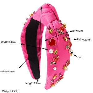Pink knotted headband with rhinestones, pearls, and heart charms on a satin fabric