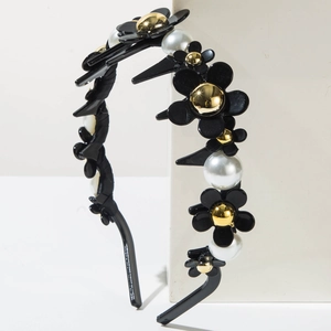 Détail d'un serre-tête floral avec fleurs noires, perles blanches et dents antidérapantes