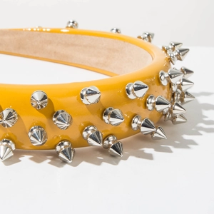Detail of yellow patent leather headband with silver punk cone studs and smooth inner lining