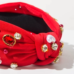 Macro-detail van rode geknoopte hoofdband met strass, hartparel en kristallen accenten